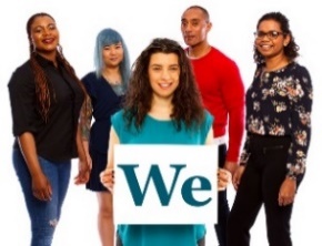 A group of people. There is a person in front holding a card that says 'We'.