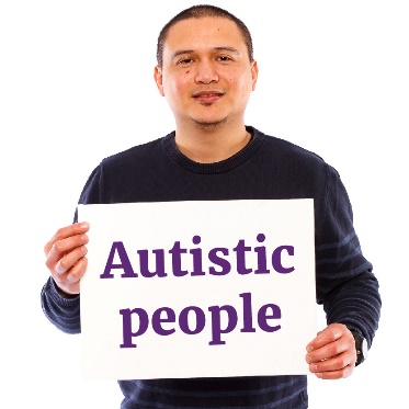 A person holding a sign that says 'autistic people'.