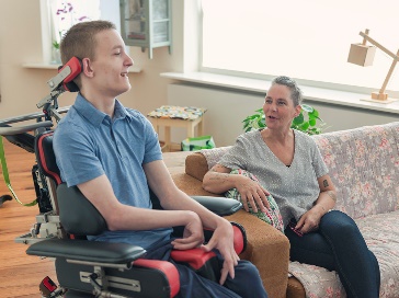 A person in a wheelchair having a conversation with a carer.