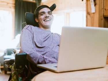 A person smiling and using a laptop.