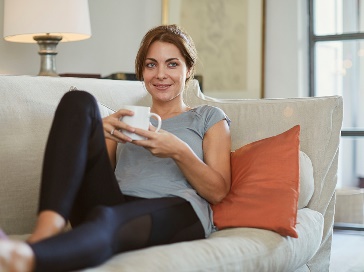 A person relaxing on a couch with a cup of tea.